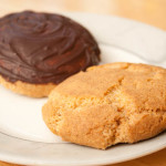 Two Grantham Gingerbread biscuits / cookies on a plate. One of the gingerbreads has been coated with dark chocolate on top.